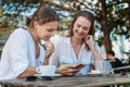 Two young women friends are sitting in a cafe drinking coffee and discussing the news, joyful and happy coffee break Royalty Free Stock Photo