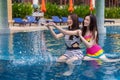 Two young woman friends splashing water in swimming pool