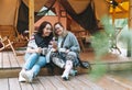 Two young women friends using mobile phone relaxing in glamping in the woods Royalty Free Stock Photo