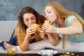 Two young women greedily eating burgers and chips Royalty Free Stock Photo