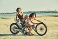 Two young women have fun playing on a disassembled motorcycle .