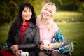 Two young women have a good time in a city park. Girlfriends in a city park on a picnic on a warm evening at sunset. Royalty Free Stock Photo