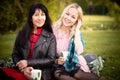 Two young women have a good time in a city park. Girlfriends in a city park on a picnic on a warm evening at sunset. Royalty Free Stock Photo