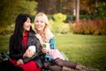 Two young women have a good time in a city park. Girlfriends in a city park on a picnic on a warm evening at sunset. Royalty Free Stock Photo