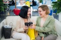 Two young women having coffee break together at shopping mall Royalty Free Stock Photo