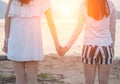 Two young women hold hands together on seaside