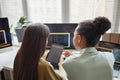 Two young women holding digital tablet with code