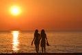 Two young women holding hands walking barefoot with slippers in his hand on the beach Royalty Free Stock Photo