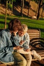 Two young women holding their smartphone, sitting on the bench in the park. Lesbian couple using their phones while Royalty Free Stock Photo