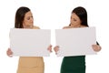 Two young smiling women holding two pieces of blank paper, looking down on papers Royalty Free Stock Photo