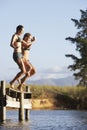 Two Young Women Jumping From Jetty Into Lake Royalty Free Stock Photo