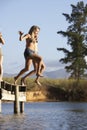 Two Young Women Jumping From Jetty Into Lake Royalty Free Stock Photo