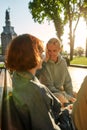 Two young women looking at each other with love while talking, sitting on the bench in the park. Lesbian couple spending Royalty Free Stock Photo