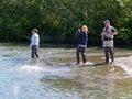 Two young women and a man guide salmon fishing in small river in