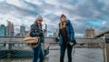 Two young women in New York walk along the typical skyline at Brooklyn Bridge