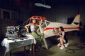 Two young women painting a body plane in airplane hangar. Royalty Free Stock Photo