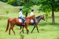 Two young women riding horse in park.