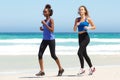 Two young women running by water on beach Royalty Free Stock Photo