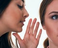 Close up shot of two young women sharing their secrets, studio shot. Royalty Free Stock Photo