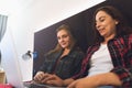 Two young women sitting in bed, looks at laptop screen and talking. Female couple or just friends spend time together Royalty Free Stock Photo