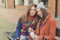 Two young women sitting on the bench outside