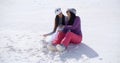 Two young women sitting chatting in the snow Royalty Free Stock Photo