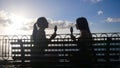 Two young women are sitting with the icecream on the bench on the waterfront