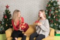 Two young women sitting on sofa holding gift box with happy expression In a room decorated for Christmas Royalty Free Stock Photo