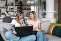 Two young women sitting on the sofa using laptop computer and credit card for online shopping and ordering groceries and food for Royalty Free Stock Photo