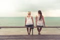 Two young women sitting together and looking into the distance on beach. Concept for togetherness Royalty Free Stock Photo