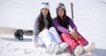 Two young women sitting waiting in the snow Royalty Free Stock Photo