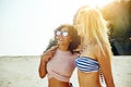 Two smiling female friends walking along a beach in summer Royalty Free Stock Photo