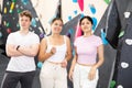 Two young women and teen guy posing against rock climbing wall Royalty Free Stock Photo