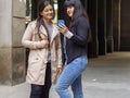 Two young women standing on a city street looking on a cellphone. Royalty Free Stock Photo