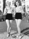 Two young women standing together playing horse shoes Royalty Free Stock Photo