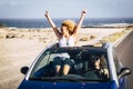 Two young women traveling in a convertible car and having fun during journey. Young woman posing with v sign while friend driving Royalty Free Stock Photo