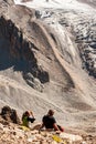 Two young women trekkers descending from top of Pik Uchitel peak with cross. Ala Archa Alpine National Park Landscape near Bishkek