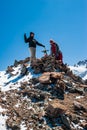 Two young women trekkers standing on top of Pik Uchitel peak with cross. Ala Archa Alpine National Park Landscape near Bishkek,