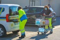 Two young women in uniform volunteer buying groceries. Girls loading car with food and water supplies.Yellow gillet,face mask on