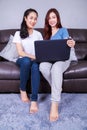 Two woman using a laptop computer on sofa in living room at home Royalty Free Stock Photo