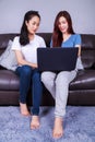 Two woman using a laptop computer on sofa in living room at home Royalty Free Stock Photo