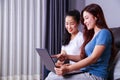 Two woman using a laptop computer on sofa in living room at home Royalty Free Stock Photo