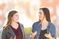 Two young women walking and talking in the street Royalty Free Stock Photo