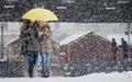 Two young women walking under umbrella in heavy snowfall in city street