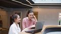 Two young women at work are engaged in discussing a work project.