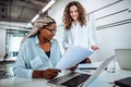 Two young women work together in a bright office. Work on the project, consultation Royalty Free Stock Photo