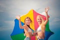 Two ypung woman aqnd coloful umbrella having fun on the beach