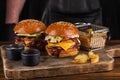 Two yummy big grilled burger with double meat cutlet and cheese on a wooden board ready to eat. Burger and fries Royalty Free Stock Photo
