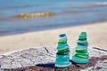 Two Zen pyramids of blue and green glass stones on wooden surface against background of coastal sea waves Royalty Free Stock Photo