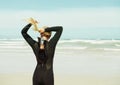 Tying back her hair for comfort during surfing. A surfer girl tying her hair into a ponytail.